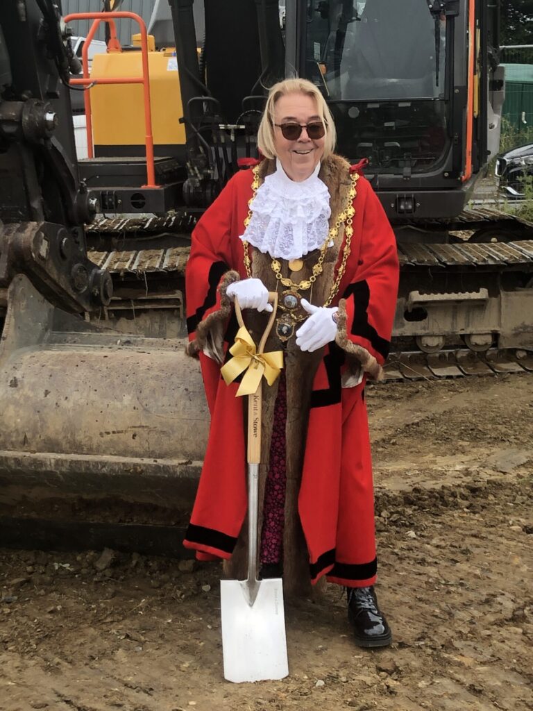 Town Mayor Rachel Clarke in full mayoral robes standing with spade after cutting ground for the new Town Ranger maintenance facility