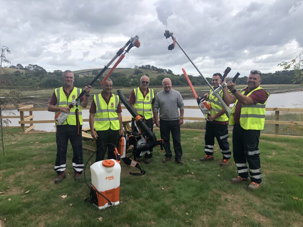 Bideford Town Rangers holding the zero carbon emission strimmers, hedge-cutter and spraying 
equipment with robust batteries meaning their work on grass verges, 
hedgerows and the smaller green spaces is cleaner, less smelly and quieter for 
both employees and residents.